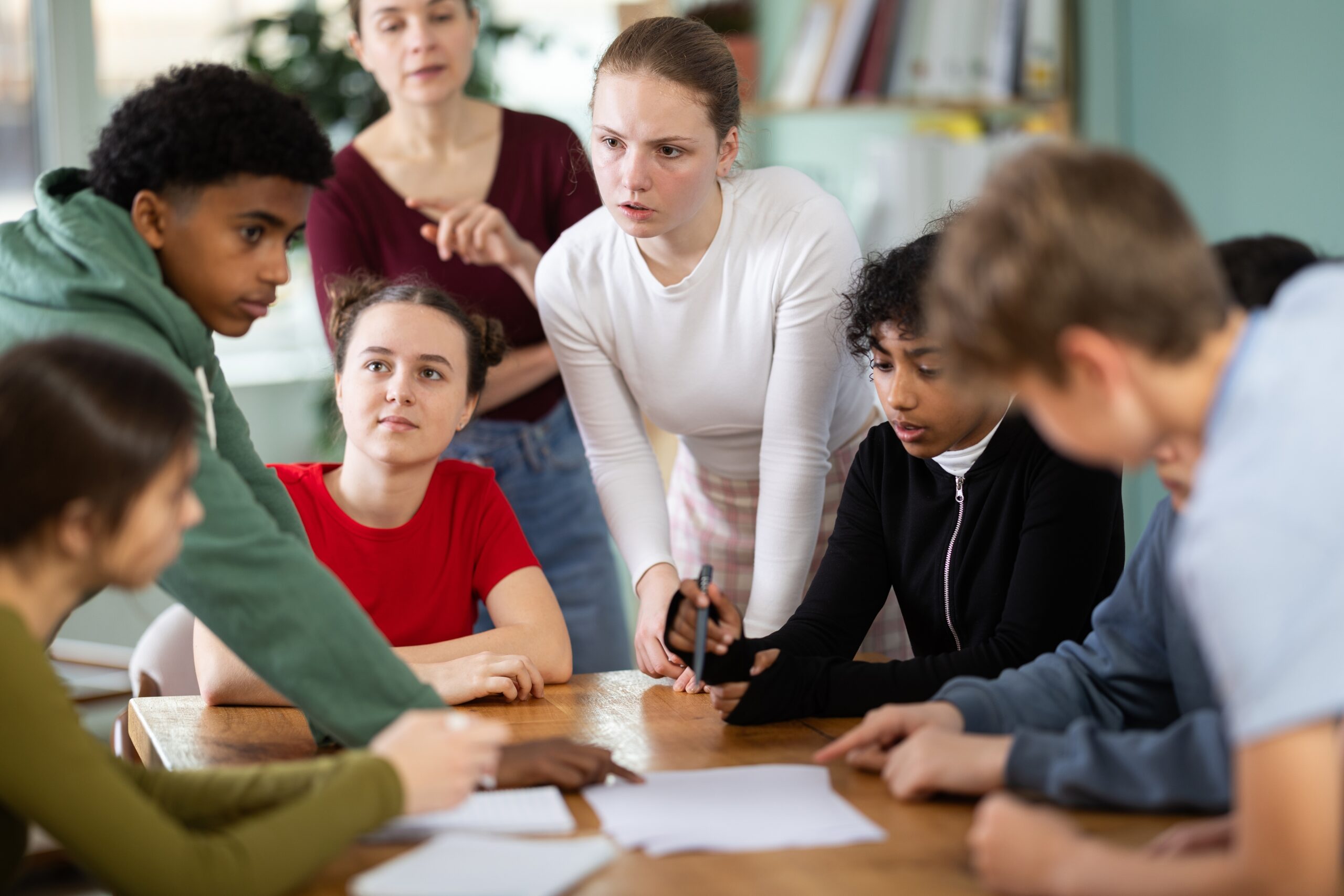 Involved,Teenage,Students,Discussing,The,Task,At,Table,While,Teacher Involved,Teenage,Students,Discussing,The,Task,At,Table,While,Teacher